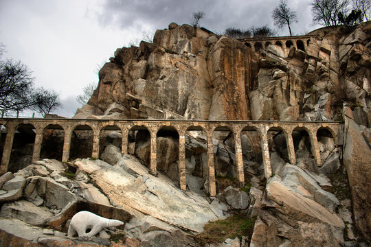 ancient roman aqueduct with arcade between the rocks and cliffs of an old medieval epic fantasy city like a fortress, on a gray cloudy sky - Landscape of Plovdiv, Bulgaria