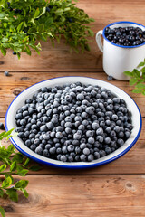Fototapeta na wymiar Frozen blueberries in a metal bowl on wooden table