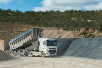 Truck in an aggregate quarry with the dump raised after downloading gravel.