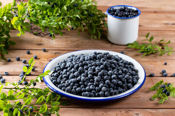Frozen berries: blueberries in a metal bowl on rustic wooden table. Frozen berries.