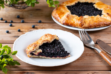 Piece of blueberry pie on a plate on wooden table