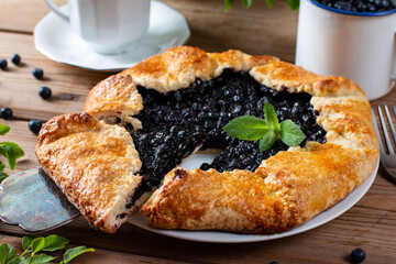 A piece of homemade galette with blueberries in a white plate on a culinary background. Delicious sweet pastries