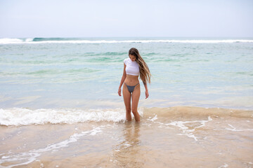 Fototapeta na wymiar Slim young woman walks into the ocean.