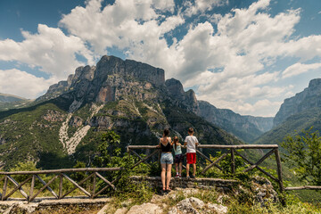 Naklejka premium Family (mother, son, daughter) watching panorama of beautiful Vikos George in Pindus Mountain (Vikos National Park), Greece