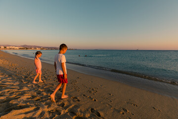 Naxos, Grece - July 20, 2020 - Siblings (girl and boy) having fun at beach during sunset over Naxos...