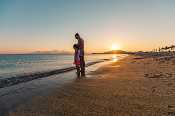 Naxos, Grece - July 20, 2020 - Mother and children watching amazing sunset over Naxos Island