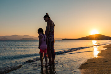 Naxos, Grece - July 20, 2020 - Mother and children watching amazing sunset over Naxos Island