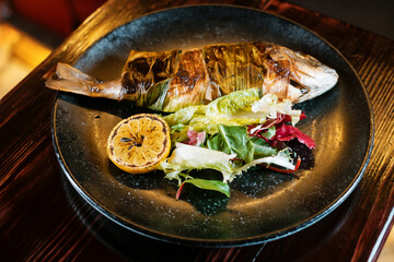 Baked fish with vegetables on black plate