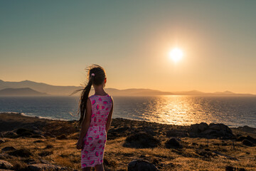 Naxos, Grece - July 20, 2020 - Girl watching amazing sunset over Naxos Island