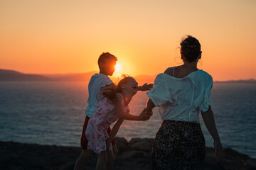 Naxos, Grece - July 20, 2020 - Mother and children having amazing time watching amazing sunset over...