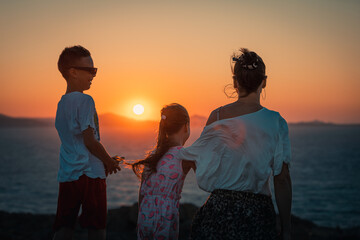 Naxos, Grece - July 20, 2020 - Mother and children having amazing time watching amazing sunset over...