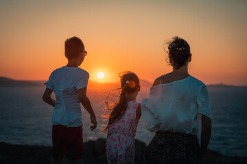 Naxos, Grece - July 20, 2020 - Mother and children having amazing time watching amazing sunset over Naxos Island - obrazy, fototapety, plakaty
