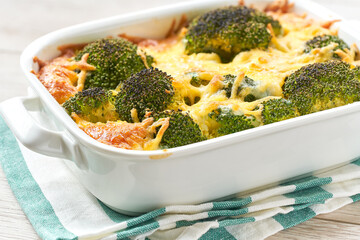 broccoli casserole with cheese, on a white wooden table.
