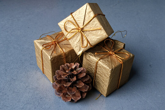 objet de d&eacute;coration avec 3 paquets cadeau dor&eacute; et un pomme de pin sur un fond gris en b&eacute;ton cir&eacute; image d'illustration pour cadeau de no&euml;l et art de la table 