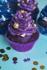 Set of chocolate cupcakes with dark blue and purple cream and golden sprinkles