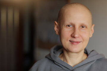 Smiling hairless young female patient struggle with oncology look at camera at home. Bald cancer...