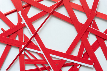 red paper stripes (cutouts) arranged in a nest pattern on blank paper