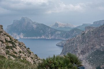 Exploring the rugged coastline of Mallorca with misty mountains and cloudy skies