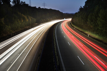 white and red traces of light from moving cars on highway at night six lines autobahn car road long...