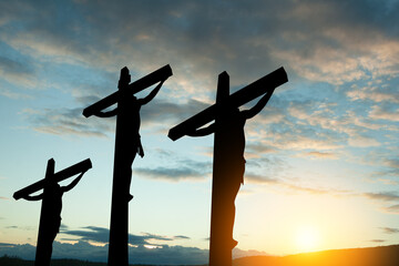 Silhouette of the crucified Jesus Christ on the cross along with other people on background of...