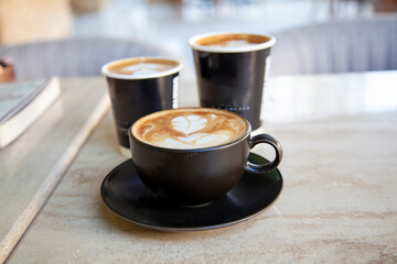 three cups of coffee on black rustic background with beautiful latte art