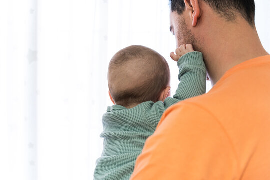 Baby held in father's arms both unrecognizable