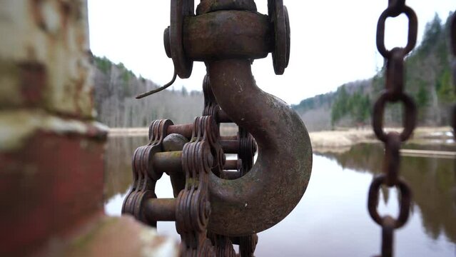 an old chain with a hook hangs by the river