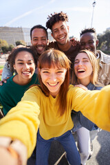 Vertical photo of a Group of happy friends posing for a selfie on a spring day as they party together outdoors. Group of multicultural friends having a good time together on the weekend. - obrazy, fototapety, plakaty