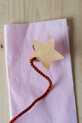 paper star and decorative pipe cleaner on folded pink tissue paper and wood