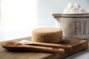 Baking ingredients in measuring spoons and bowls sit on a white marble surface and wooden cutting board.