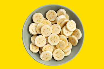 Banana slices in bowl on yellow background.