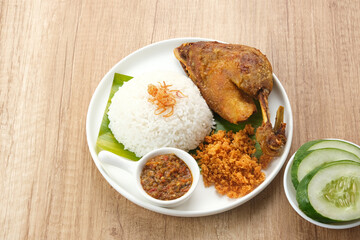 Bebek Goreng Kremes, served with chili sauce (sambal) and cucumber. Indonesian food
