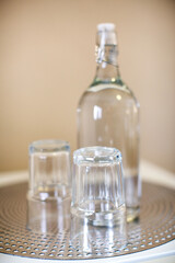 Two small drinking glasses and an empty water bottle