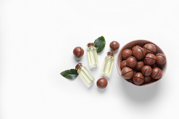 Delicious organic Macadamia nuts, green leaves and natural oil on white background, flat lay. Space for text