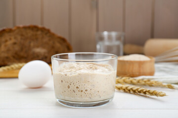 Glass jar with sourdough on white wooden table