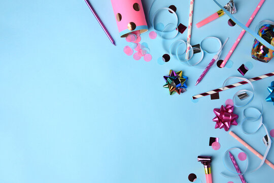 Party popper with confetti, blower and festive decor on light blue background, flat lay. Space for text