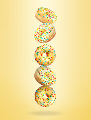 Obraz na płótnie Canvas Tasty donuts with sprinkles falling on pastel golden background