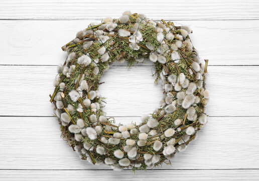Wreath made of beautiful willow flowers on white wooden table, top view