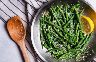 Green beans with Parmesan cheese in a frying pan with lemon