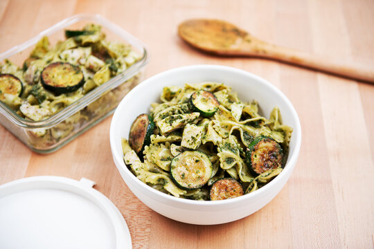 Pasta salad being prepared with bowtie pasta, zucchini, cheese and pesto