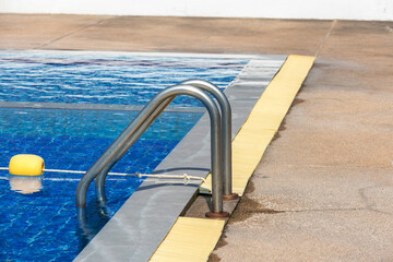 Ladder stainless handrails for descent into swimming pool. Swimming pool with handrail . Ladder of a swimming pool. Horizontal shot. stairs swimming pool. Stainless steel ladder
