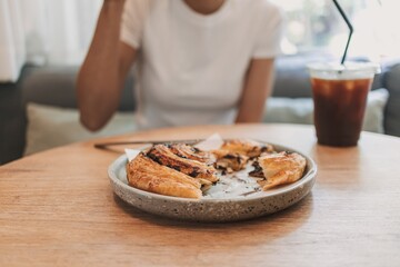 Woman is eating kind of dessert bread in the cafe.
