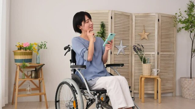 リビングでスマホを使いながら想像する車椅子に乗った女性