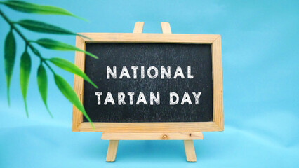 Happy National Tartan Day inscription on black chalkboard. Celebration of Scottish heritage on April 6. Tartan Week.