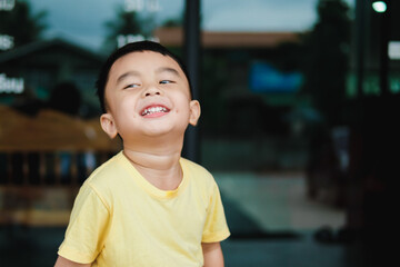 Smiling Asian boy in yellow t-shirt. Blurred background.