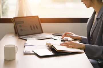 A cropped shot shows a millennial businesswoman of a startup working with financial report paperwork in her home office. The concept of financial advising teamwork and accounting is depicted.