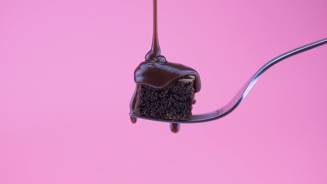 Chocolate Brownie slice on a fork with almonds, and pouring melted chocolate on top