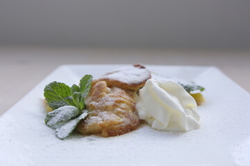 Serving pancakes on plate. With ice cream and mint and powdered sugar square plate close up...