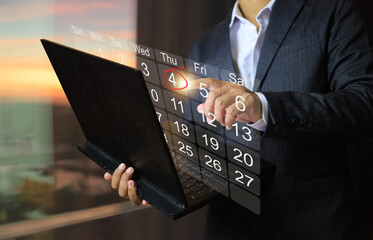 Businessman pointing at calendar on computer screen and setting date to plan start a new project or finish deadline Or schedule a meeting of the relevant departments to update progress.