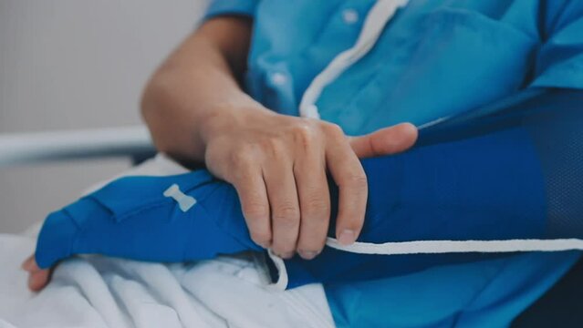 Man with broken arm in cast lying on bed in hospital. The emergency center treatment is plaster and hangs with sling for a further cure in an orthopedic clinic. Patient pain from accident injury.